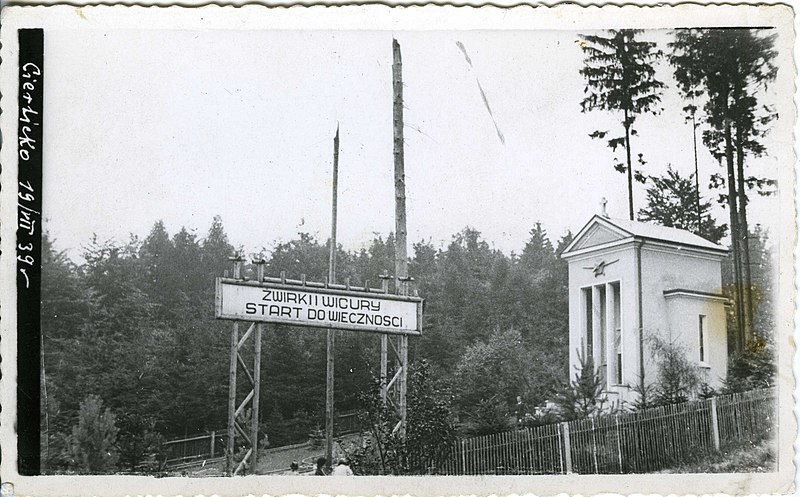 Widok ogólny Żwirkowiska, 19.07.1939, w tle widoczne dwa ułamane drzewa, tzw. maszty śmierci, i brama z napisem „Start do wieczności”, wg fotografii nieznanego autora