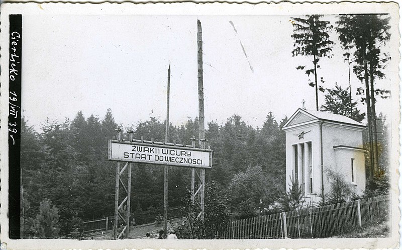 Widok ogólny Żwirkowiska, 19.07.1939, w tle widoczne dwa ułamane drzewa, tzw. maszty śmierci, i brama z napisem „Start do wieczności”, wg fotografii nieznanego autora
