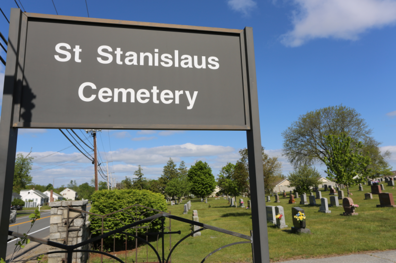 Zdjęcie bramy cmentarza z ciemni-szarą tablicą 