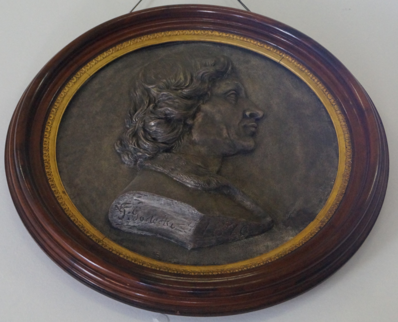 Ciemnobrązowy okrągły medalion z profilem Mikołaja Kopernika